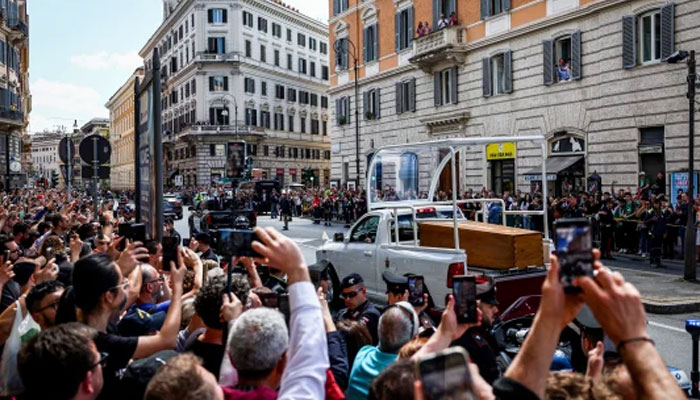 People take pictures of the coffin of late Pope Francis as it is transported on a popemobile in Rome on April 26, 2025. — AFP