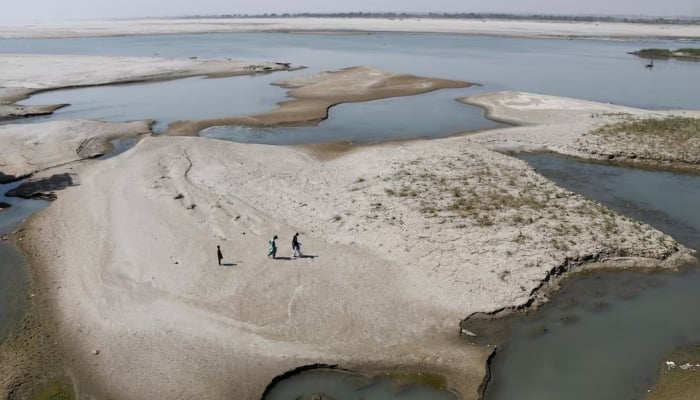 People walk on the dry patch of the Indus River, in Jamshoro, on March 15, 2025. —Reuters