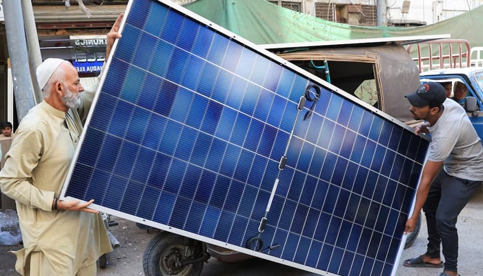 Men load solar panels on a rickshaw (tuk tuk) at a market, in Karachi, on March 26, 2025. — Reuters
