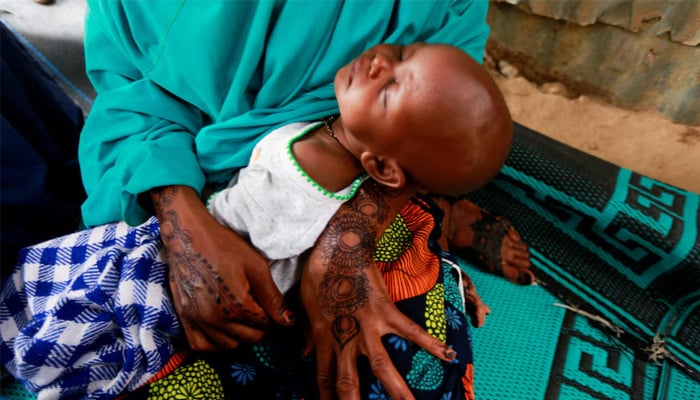 A mother carries her sleeping baby during a safety training workshop for displaced Boko Haram victims on the identification of dangerous objects, at the Gubio camp in Maiduguri, Nigeria May 6, 2022. Picture taken May 6, 2022. — Reuters