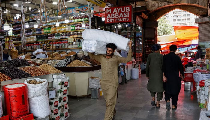 A man walks with sacks of supplies on his shoulder to deliver to a nearby shop at a market in Karachi. — Reuters/File