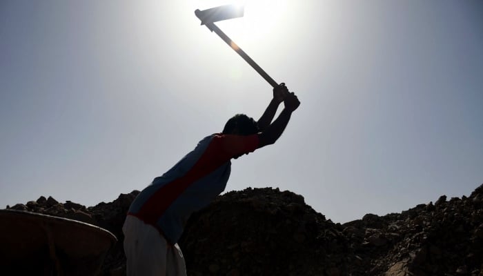 A labourer uses an axe at a work site in Karachi. — Online/File