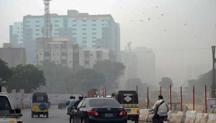 Commuters pictured on MA Jinnah Road near Numaish Chowrangi in Karachi during strong winds. — AFP/File