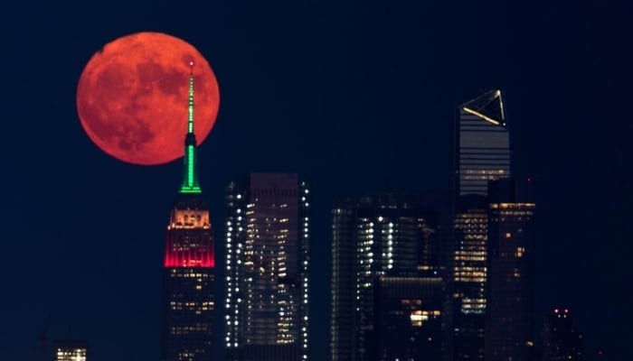 A full moon rises behind the Empire State Building in New York City, New York, US, July 23, 2021. — Reuters