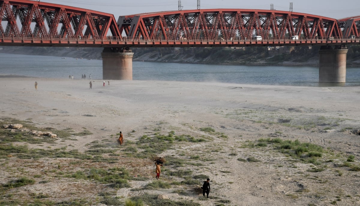 People walk on the dry riverbed of the Indus River in Hyderabad on April 24, 2025. — Reuters