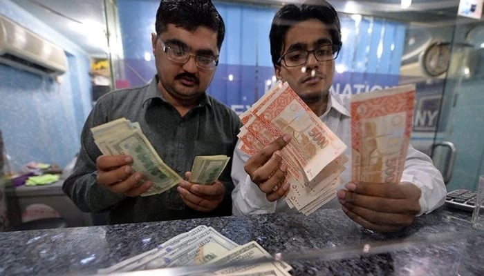 Silver dealers have Pakistani rupees, right and US dollars in a change in Islamabad. - AFP / File