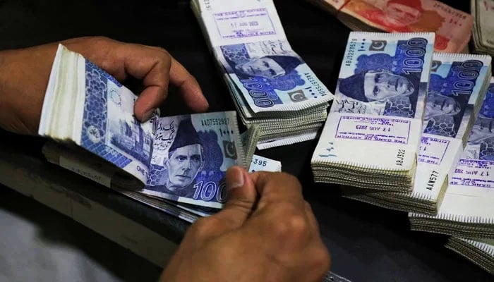 A bank employee counts Pakistani rupee notes at a bank in Peshawar, on August 22, 2023. — Reuters