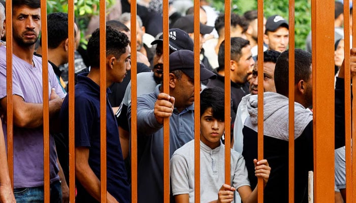 People watch through the rails of the gate of a hospital where the bodies of Palestinians killed in the Israeli strikes are kept, in Khan Younis, southern Gaza Strip October 10, 2023. — Reuters