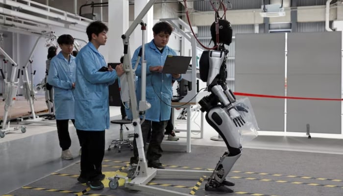Employees work on the production line of humanoid robots at the AgiBot factory in Shanghai, China March 20, 2025. — Reuters