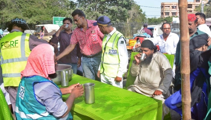 Volunteers give water to people in a heatwave camp amid hot and humid weather in Karachi on May 21, 2024. — APP