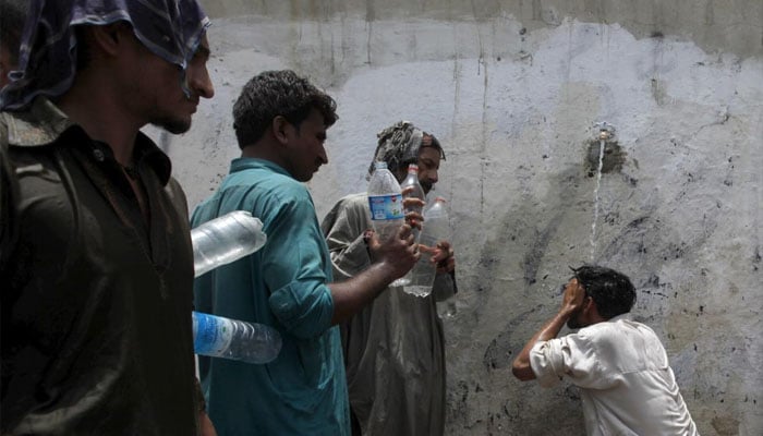 A man cools off under a public tap, while others wait to fill their bottles, during intense hot weather in Karachi, Pakistan, June 23, 2015 — Reuters