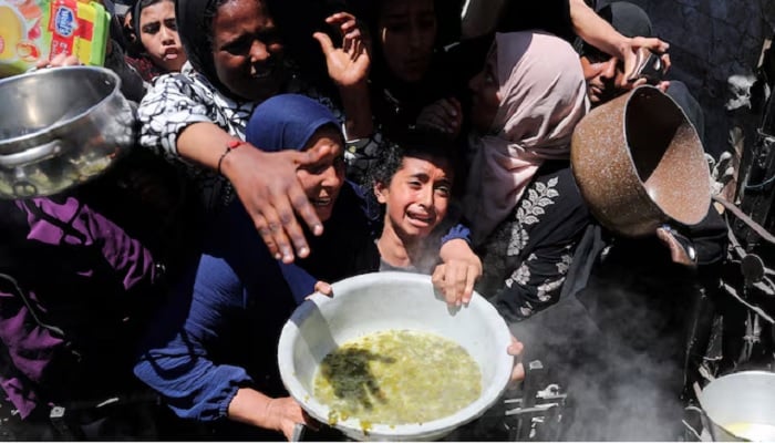 A Palestinian receives food cooked by a charity kitchen, in Beit Lahia, northern Gaza Strip, May 8, 2025.— Reuters