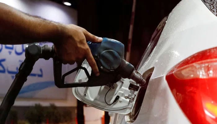 A worker holds a fuel nozzle to fills fuel in a car at petrol station in Karachi, on September 16, 2023. — Reuters