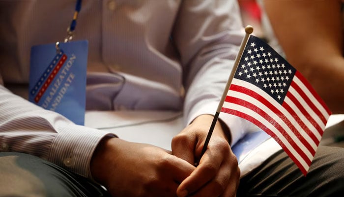 A new citizen holds a U.S. flag at the U.S. Citizenship and Immigration Services (USCIS) naturalization ceremony at the New York Public Library in Manhattan, New York, U.S., July 3, 2018. — AFP