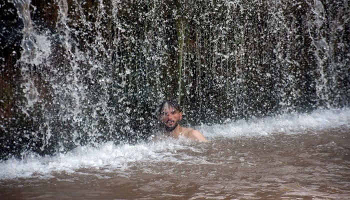 A youngster cools himself off in the waterfall of Angori during high temperature in Islamabad on May 15, 2025. — Online