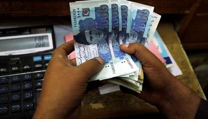 A trader counts Pakistani rupee notes at a currency exchange booth in Peshawar, Pakistan December 3, 2018. — Reuters
