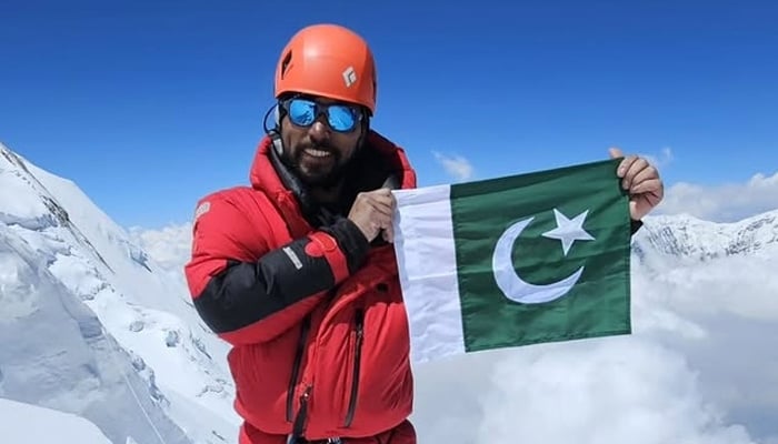 Pakistani mountaineer Sirbaz Khan displays the national flag as he poses for a picture after scaling a mountain. — Instagram@sirbazkhan_mission14