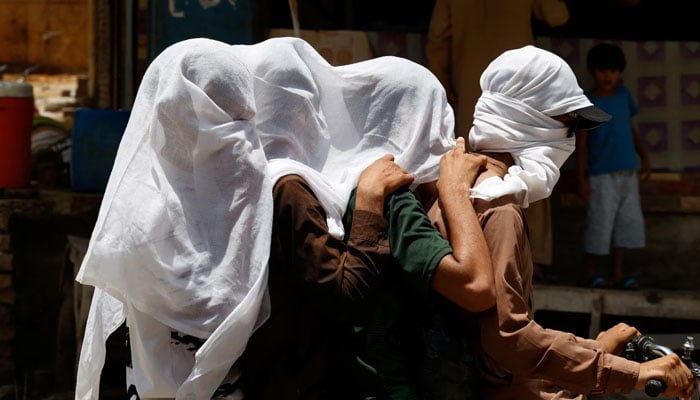 Men ride on a motorbike as they cover their heads with a wet cloth to cool off and to avoid sunlight, during a hot summer day, as the heatwave continues in Jacobabad, Pakistan May 26 — Reuters