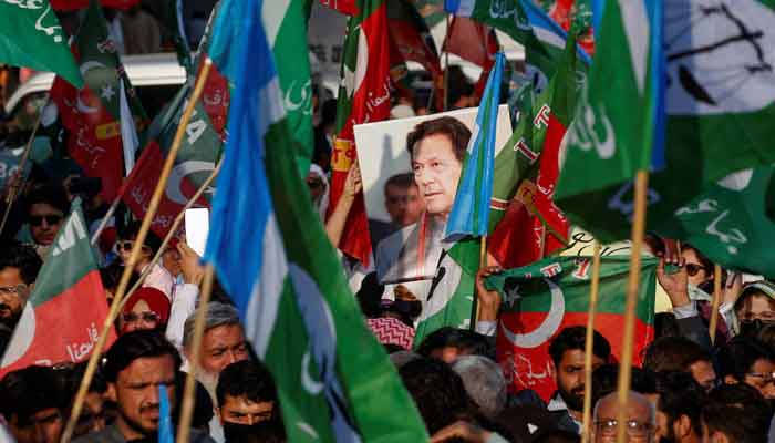 A portrait of the former Prime Minister Imran Khan is seen amid flags of PTI and Jamat-e-Islami as supporters attend a joint protest in Karachi, on February 10, 2024. — Reuters