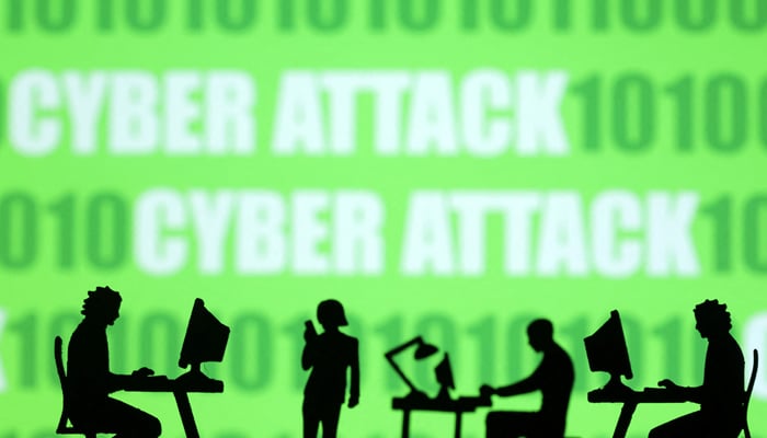Miniatures of people with computers are seen in front of binary codes and words Cyber attack in this illustration taken July 19, 2023. — Reuters