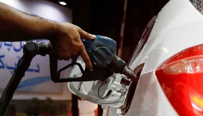 A worker holds a fuel nozzle to fills fuel in a car, after the government announced the increase of petrol and diesel prices, at petrol station in Karachi. — Reuters/File