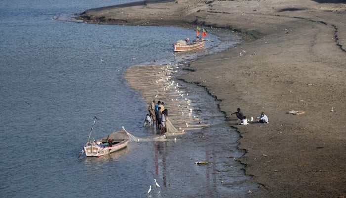 Fishermen clear a fishing net in the water on the partially dried up riverbed of the Indus River in Hyderabad, April 25, 2025. — Reuters