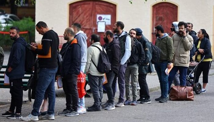 Migrants queue in a waiting area to be escorted to a registration office at the arrival centre for asylum seekers in Reinickendorf district, Berlin, Germany, October 6, 2023. — Reuters