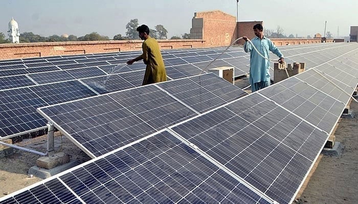 Workers washing 300 KWP solar PV system after its installation on December 4, 2022. — APP/File