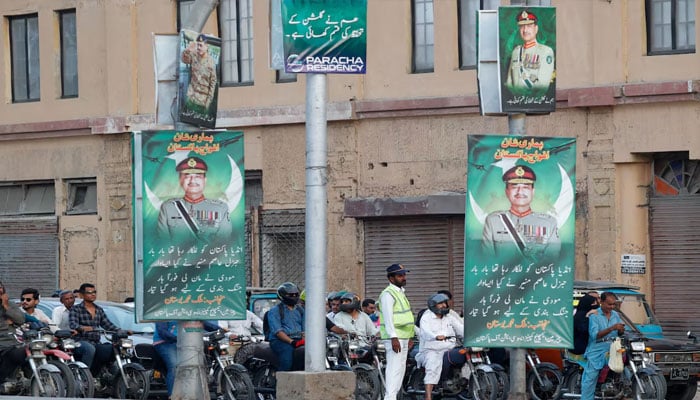A police officer stands in front of the traffic, next to posters of the Chief of Army Staff of Pakistan Asim Munir, in Karachi, Pakistan May 20, 2025. — Reuters