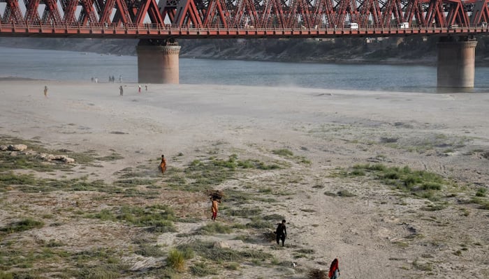 People walk on the dry riverbed of the Indus River in Hyderabad on April 24, 2025. — Reuters