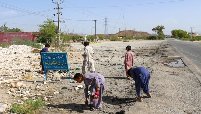 Local boys inspect site of a school bus bombing in Khuzdar district of Balochistan province on May 21, 2025. — AFP