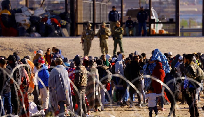 Migrants stand near the border wall after crossing the Rio Bravo river with the intention of turning themselves in to the US Border Patrol agents, as seen from Ciudad Juarez, Mexico, April 14, 2023. — Reuters