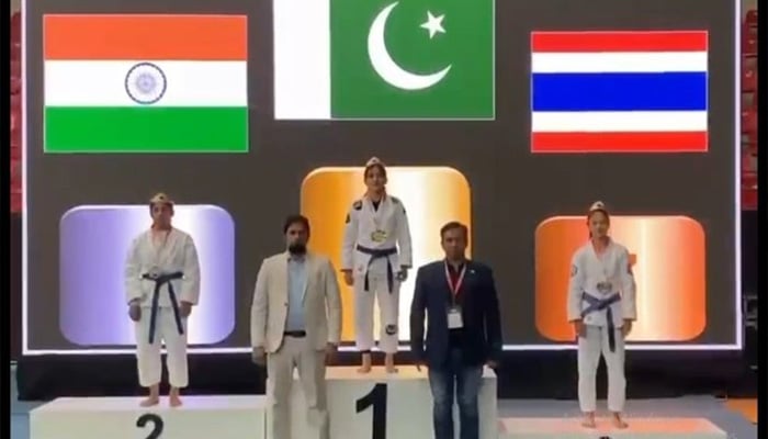 Pakistani athlete Bano Kousar stands on the top podium after clinching gold in an Asian Ju-Jitsu Championship alongside Indian and Thailand atheletes on May 25, 2025. — Reporter