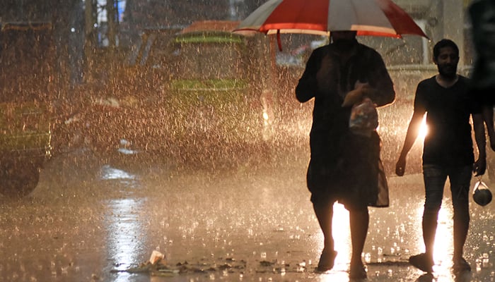People are on their way on a road during heavy rain in Rawalpindi, on May 24, 2025. — Online