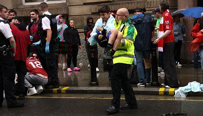 A paramedic carries a child after multiple people were hit by a car during the Victory parade in Liverpool, Britain on May 26, 2025. — Reuters