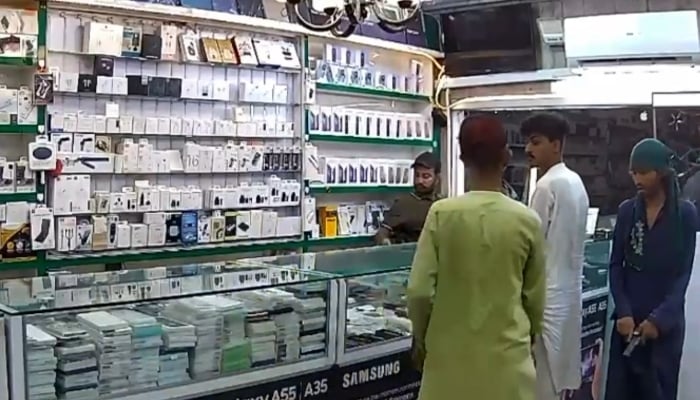 Screengrab from CCTV footage of armed robbery in Badr Commercial mobile shop, Karachi. — Reporter