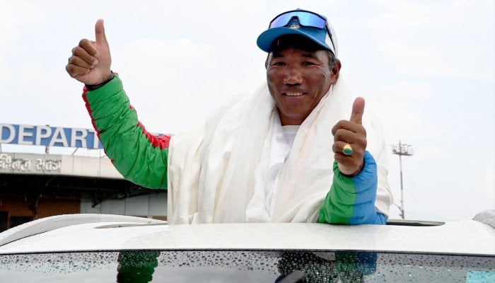 Nepali mountaineer Kami Rita Sherpa gestures to the crowd upon his arrival at the Tribhuvan International Airport in Kathmandu on May 24, 2024. — AFP