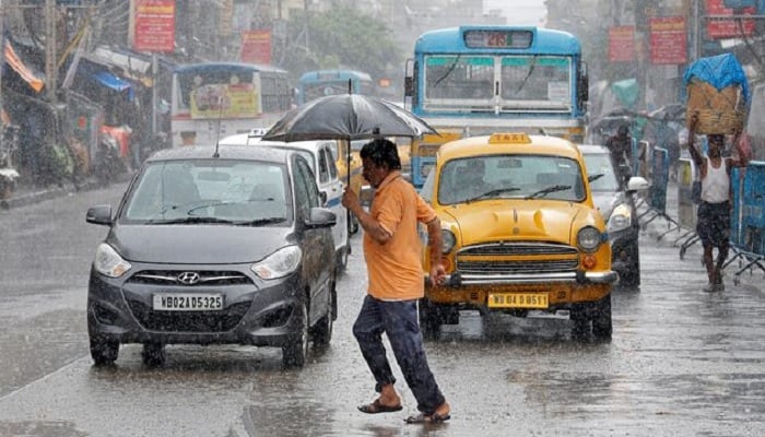 A man carrying an umbrella runs as he crosses a busy road during rain in Kolkata, India. — Reuters/File