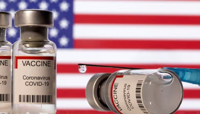 Vials labelled VACCINE Coronavirus COVID-19 and a syringe are seen in front of a displayed U.S. flag in this illustration taken December 11, 2021. — Reuters