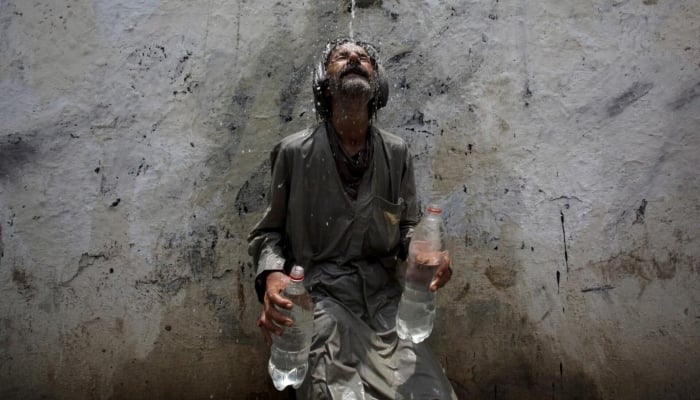 A man cools off from a public tap after filling bottles during intense hot weather in Karachi, June 23, 2015. — Reuters