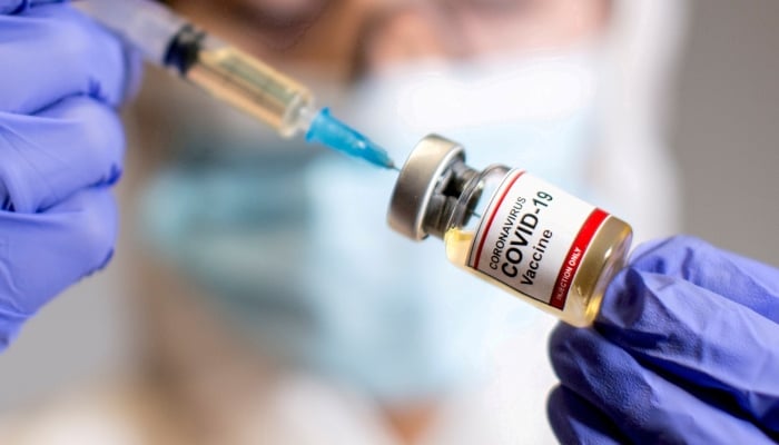 A woman holds a small bottle labelled with a Coronavirus Covid-19 Vaccine sticker and a medical syringe in this illustration taken October 30, 2020. — Reuters