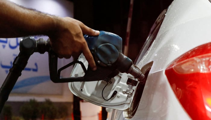 A worker holds a fuel nozzle to fills fuel in a car, after the government announced the increase of petrol and diesel prices, at petrol station in Karachi, September 16, 2023. — Reuters