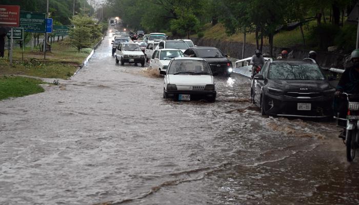Vehicles make their way through stagnant rainwater accumulated on the road near Zero Point in Islamabad after heavy rainfall on May 24, 2025. — AFP