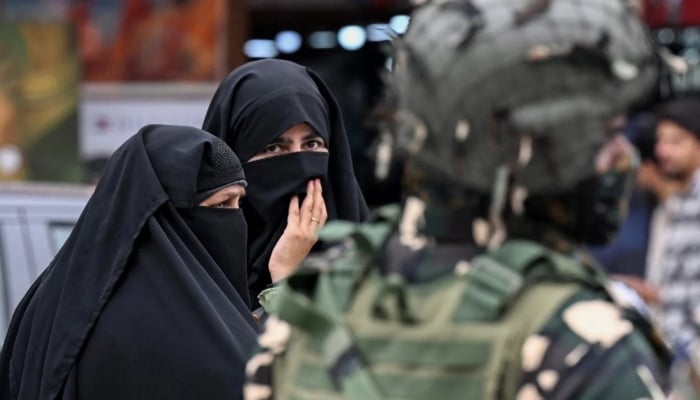 Kashmiri Muslim women walk along a street as an Indian paramilitary trooper stands guard in Srinagar, Indian Illegally Occupied Jammu and Kashmir, on May 2, 2025. — AFP