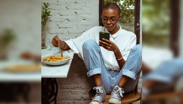 How social media can 'trigger' eating disorders in young people 1 This representational image shows a woman eating while using her phone. — Pexels