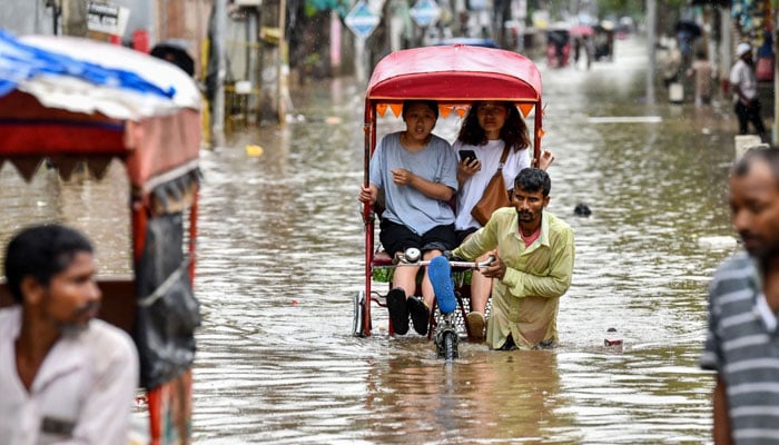 Women commute in cycle rickshaws through a flooded street after heavy rains in Guwahati, in India’s Assam state on May 31, 2025 — AFP