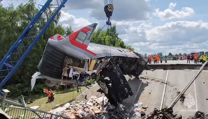 Specialists of emergency services use a crane to lift a damaged train carriage at the scene, after a road bridge collapsed onto railway tracks derailing an approaching train in the Bryansk region, Russia, June 1, 2025 — Reuters