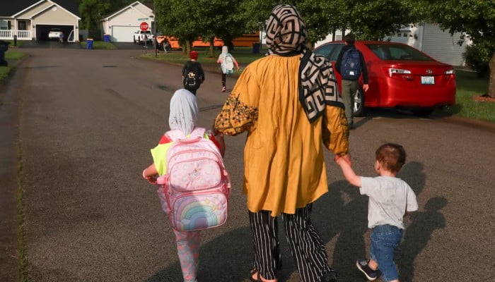An  Afghan refugee mother walks with her children to the school bus in Bowling Green, Kentucky, US, April 30, 2025. — Reuters
