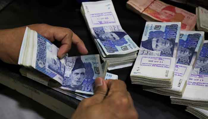 An employee counts Pakistani rupee notes at a bank in Peshawar, August 22, 2023. — Reuters