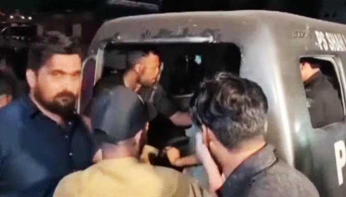 Policemen push the prisoners who had escaped into the van after recapturing them in this still taken from a video. — Geo News